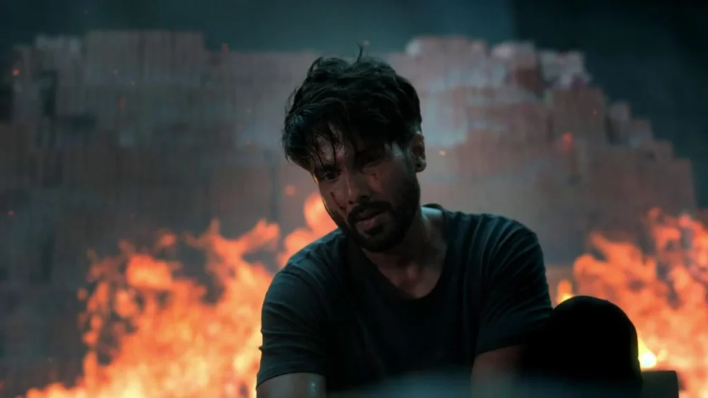Shahid Kapoor as Sunny sits before a burning building in a scene from Farzi.